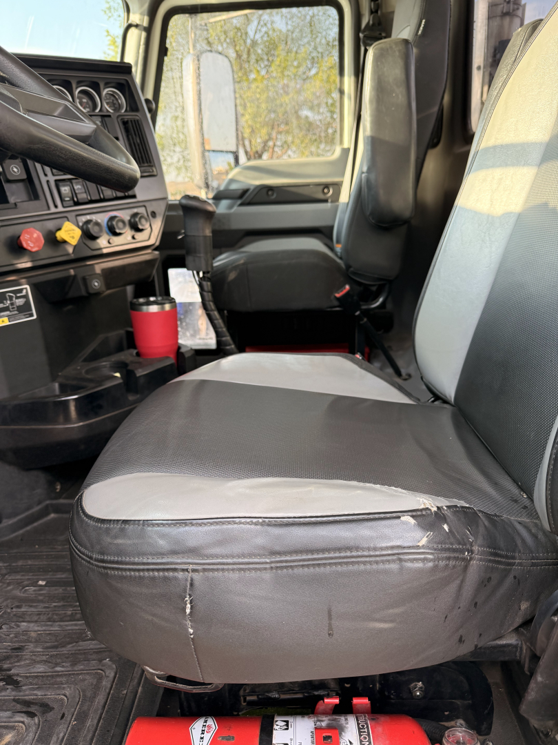 Front cab interior of a 2020 Mack Pinnacle daycab showing driver seat and passenger seat, steering wheel visible, dashboard controls, floor mats, and gear lever.