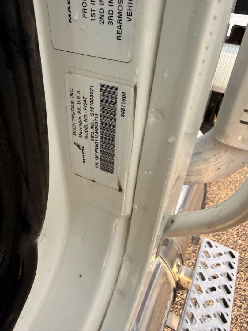 Label on door jamb and VIN plate inside truck doorway of a 2020 Mack Pinnacle conventional daycab showing vehicle VIN and stock tag.