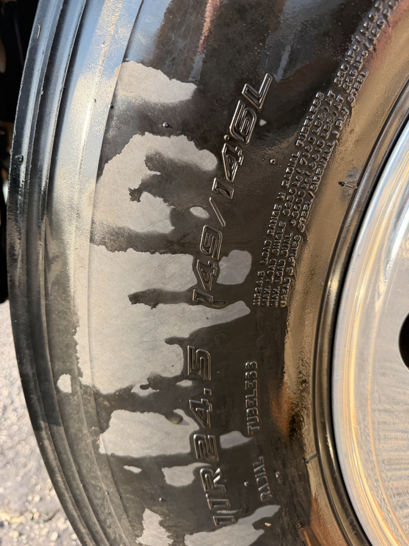 Wheel rim with embossed text reading 'MACK' and 'PINNACLE' along the tire. Close-up shows styrened lettering on wheel with surrounding metal."