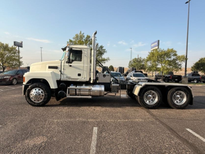 Conventional daycab truck from 2020 Mack Pinnacle side view showing white cab, chrome fuel tanks, and three-axle rear chassis.