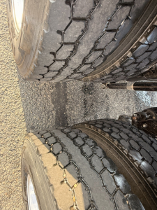 Tires visible under the axle of a Mack Pinnacle truck showing dual rear wheels with tread pattern and part of the frame.