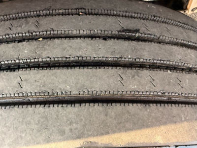 Tires stacked in a close-up view showing tread and sidewall texture on a truck wheel area.