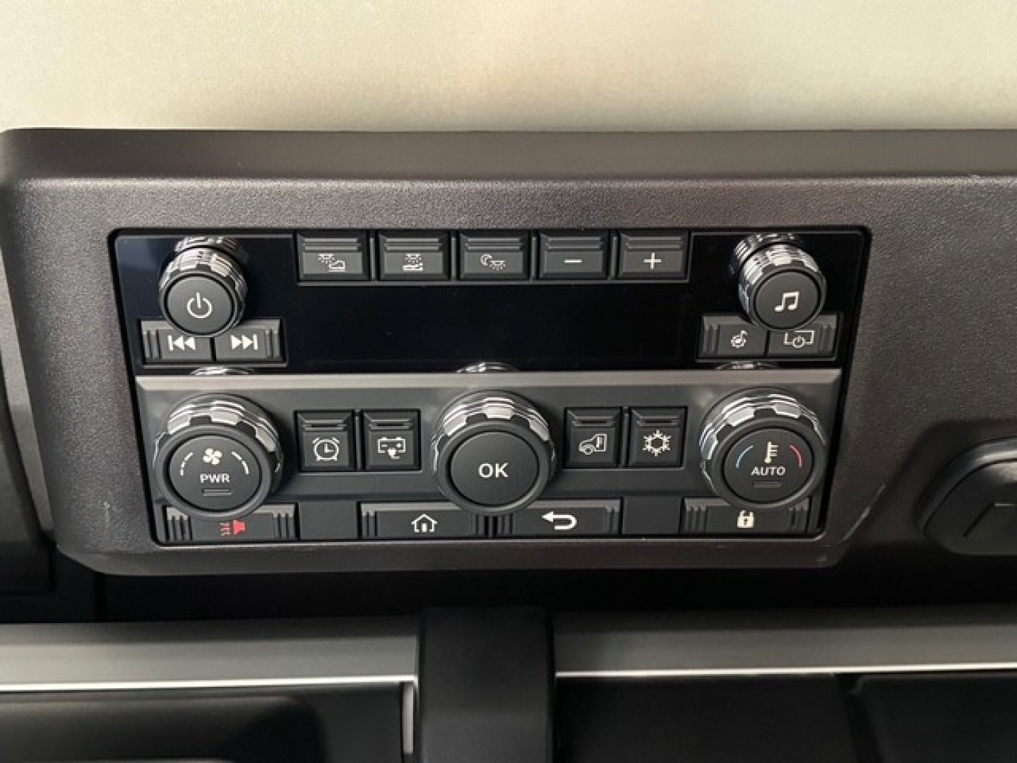 Dashboard control panel of a Mack PR64T76H truck showing multiple buttons, knobs, and a central OK dial.