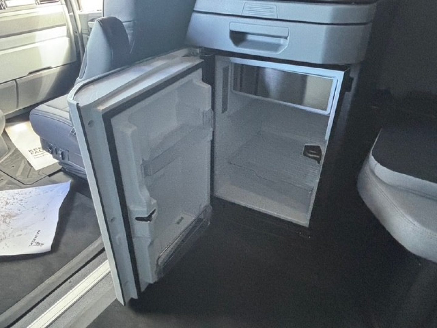 Mack PR64T76H sleeper cab interior showing open small refrigerator/freezer unit in lower cab area and empty freezer compartment.