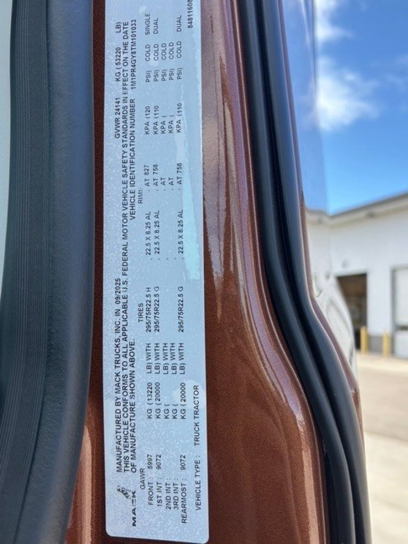 Plate with vehicle information sticker on Mack PR64T76H sleeper cab showing VIN, weight, and compliance details.