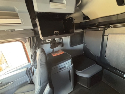 Truck cab interior of a 2026 Mack PR64T76H showing sleeper storage cabinet and ladder rack area with cabinetry and seating