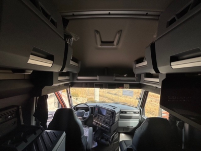 Cabin interior of a Mack PR64T76H truck showing overhead bunk storage compartments and dashboard with steering wheel