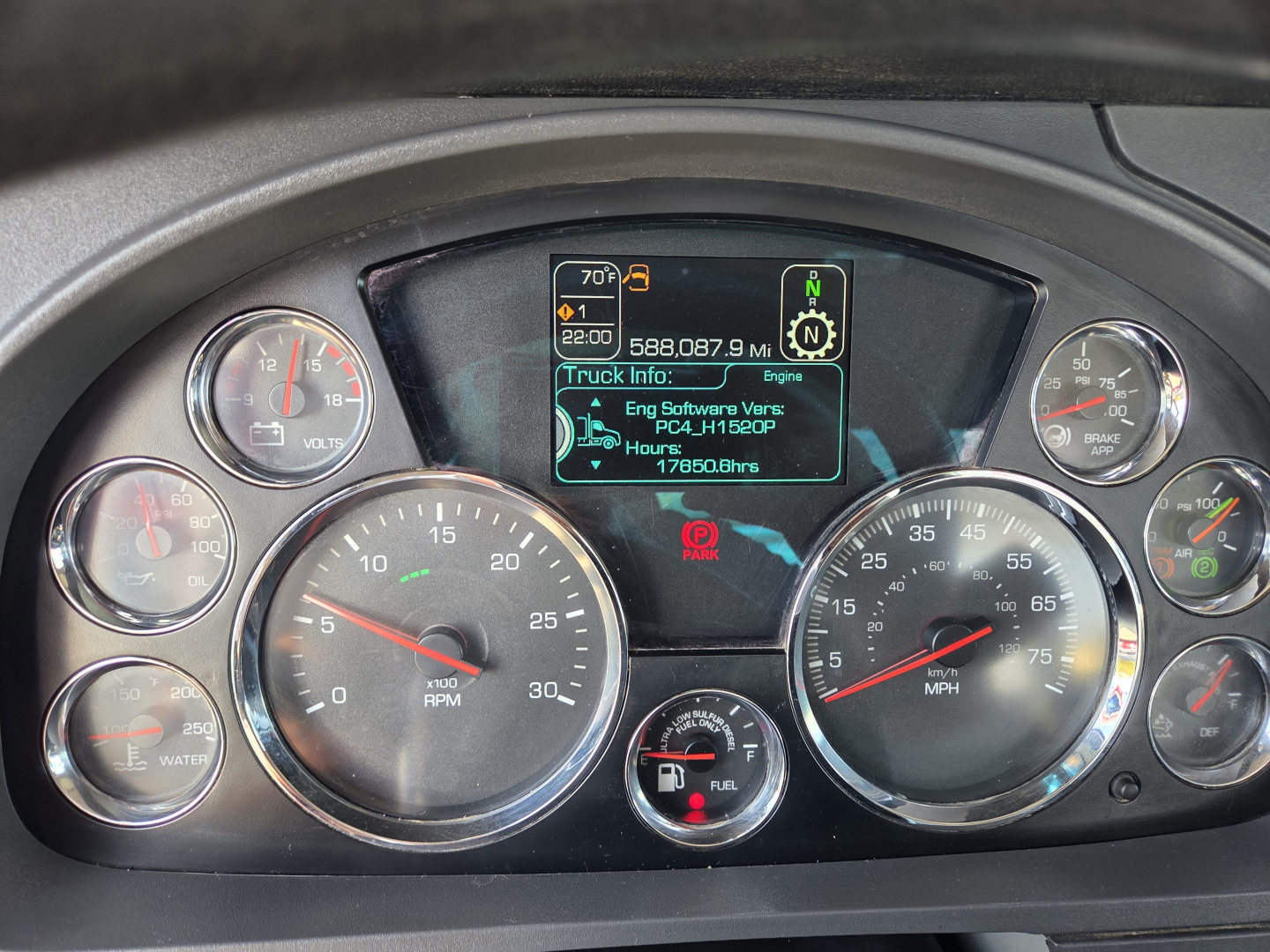 Dashboard of a Kenworth truck showing multiple gauges and a central digital display with truck info. Text on display includes 70? F? 22:00, 588,087.9 mi, Truck Info: Eng Software Ver. PC3-41 150cp? 178?  hours.
