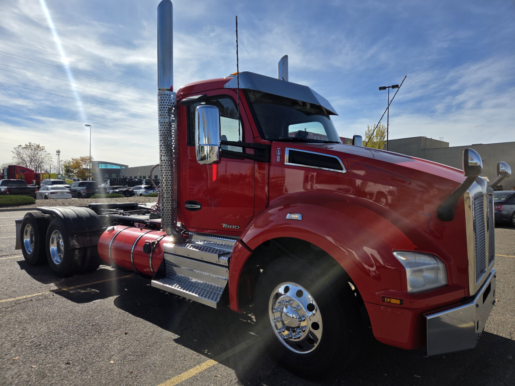 Kenworth T880 conventional daycab tractor in red, side view showing chrome exhaust stack, fuel tanks, and dual rear axles. visible VIN 1XKZDP9X2LJ428479 and stock number 0631664.
