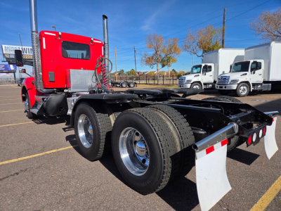 Kenworth T880 conventional daycab chassis showing dual rear axles and rear mud flaps.