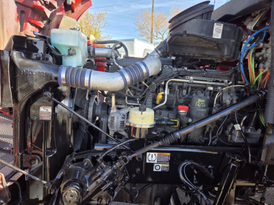 Kenworth T880 engine bay showing intake hose, coolant reservoir, wiring, and diesel engine components.