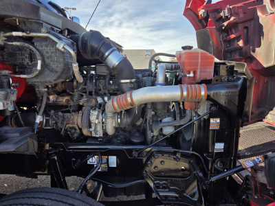Kenworth T880 engine bay showing large intake pipes, hoses, radiator area, and front chassis components.