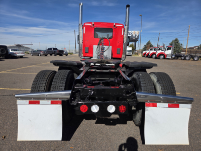 Rear view of a red Kenworth T880 truck chassis showing dual rear axles, mud flaps, and multiple warning lights.