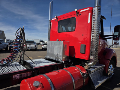 Red Kenworth T880 daytime cab showing side view with chrome exhaust stacks and diamond plate steps and fuel tank.