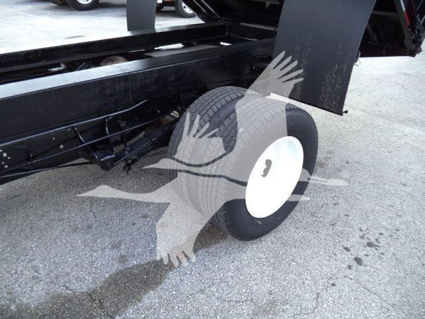 Ford E-450 wheel and chassis visible under dump body with white hubcap and black undercarriage.