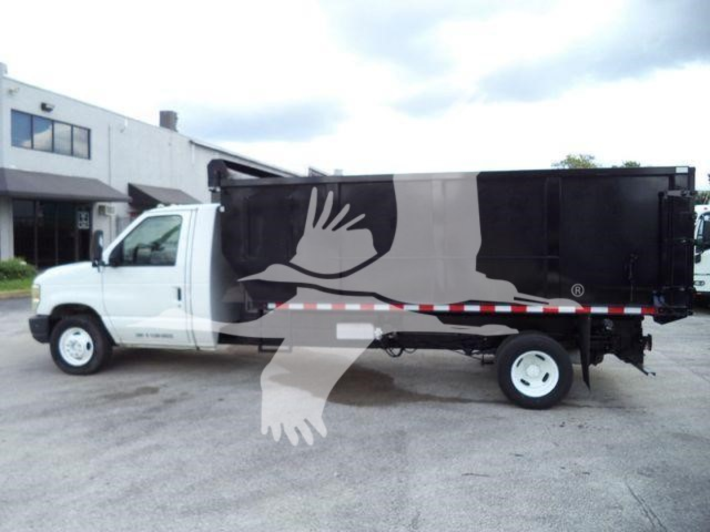 Ford E-450 dump truck in side view showing white cab and black dump body with logo watermark.