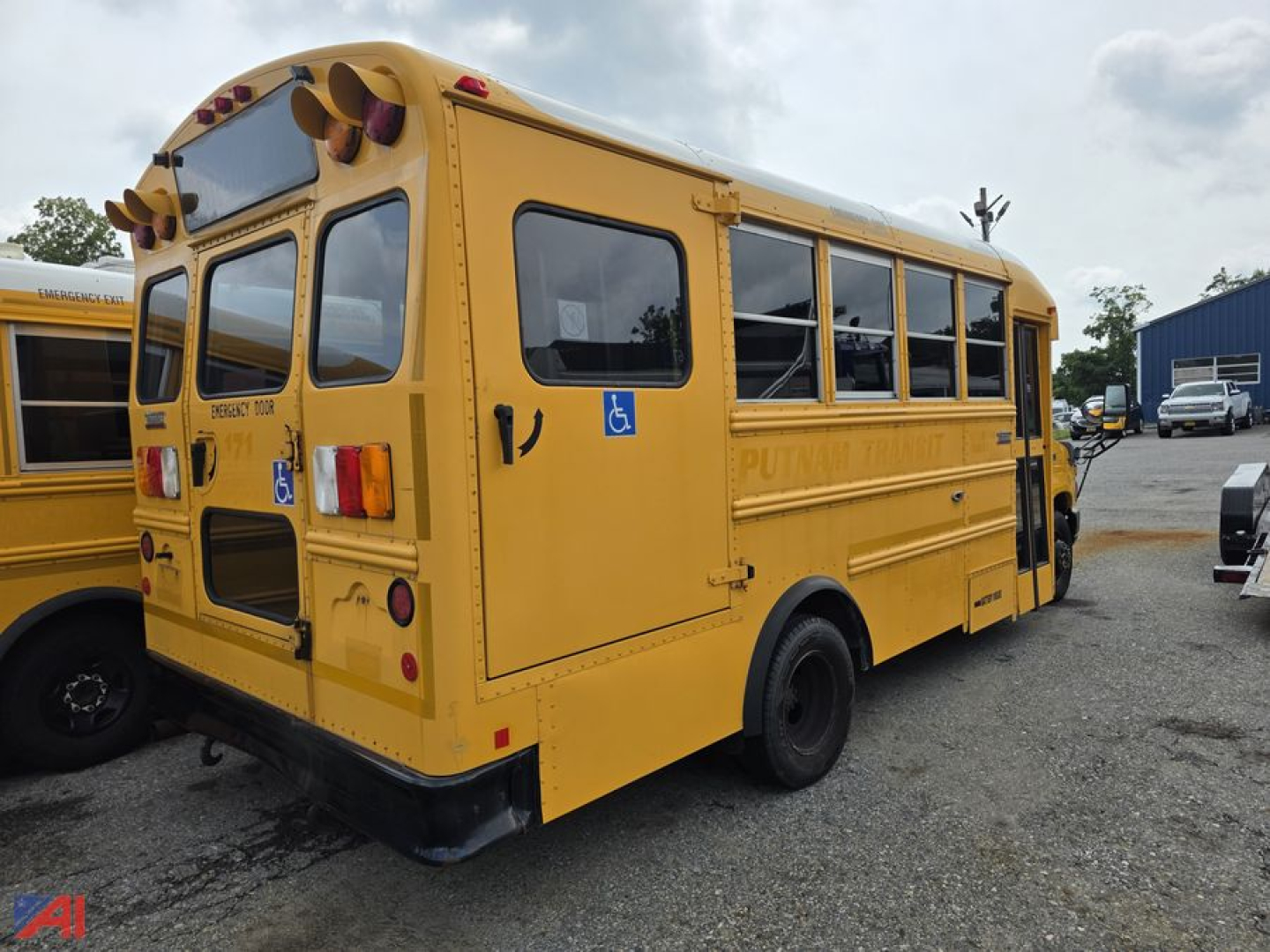 Yellow school bus rear/side view showing handicap placard area and rear doors, some text on bus sides and back; no legible serials visible.