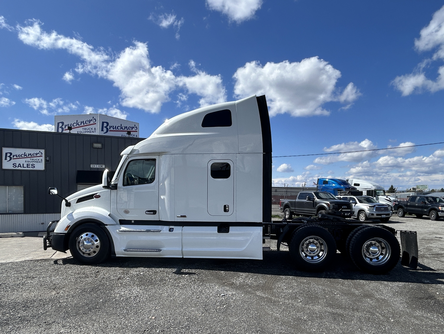 Peterbilt 579 sleeper cab truck side view showing white exterior and chassis with dual rear axles