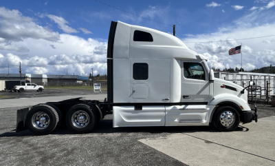 Truck side view of a 2022 Peterbilt 579 conventional sleeper tractor showing aluminum exterior, tandem rear axles, and aerodynamic cabin with windows.