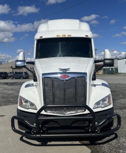 Truck front view of 2022 Peterbilt 579 conventional sleeper showing chrome grille, large bumper guard, and white cab.