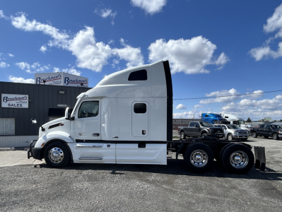 Peterbilt 579 sleeper cab truck side view showing white exterior and chassis with dual rear axles