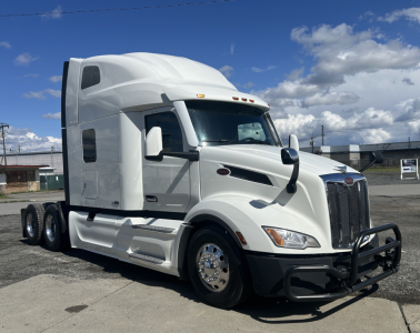 Peterbilt 579 semi-truck in white, side view, with sleeper cab and chrome wheels. No visible text on doors; cab features include aerodynamic mirrors and grille.