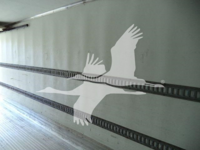 Exterior side of a refrigerated truck trailer with a large white seagull graphic on the side wall and rail tracks along the interior wall.