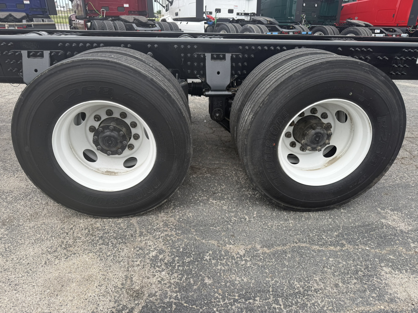 Dual rear wheels on a Volvo cab and chassis showing white steel rims and black tires with frame and suspension components visible.