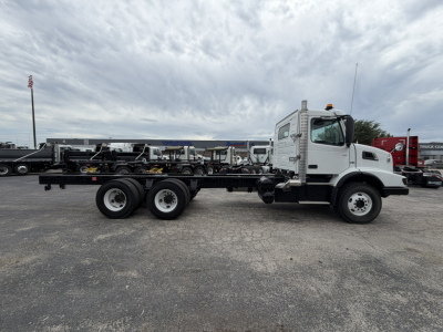 Volvo VHD86B300 cab and chassis truck side view showing triple rear axles and white cab with orange beacon on roof.