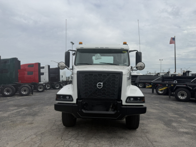 Volvo VHD86B300 cab and chassis front view showing large black grille with Volvo emblem, rectangular headlights, white cab, two amber clearance lights on top, large side mirrors.