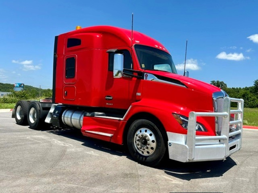 Kenworth T680 semi-truck in red with aerodynamic cab, chrome bumper guard, and dual rear wheels; side view showing cab, fuel tanks, and antenna.