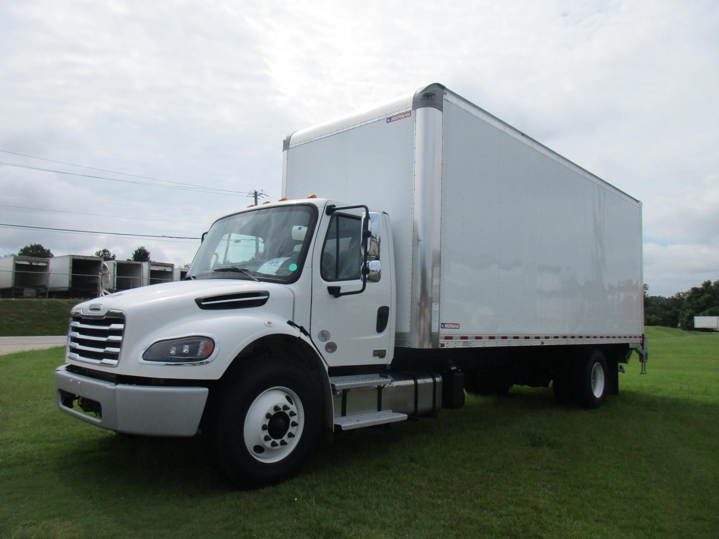 Box truck side view showing 2027 Freightliner M2 106 with white cab and large box trailer.