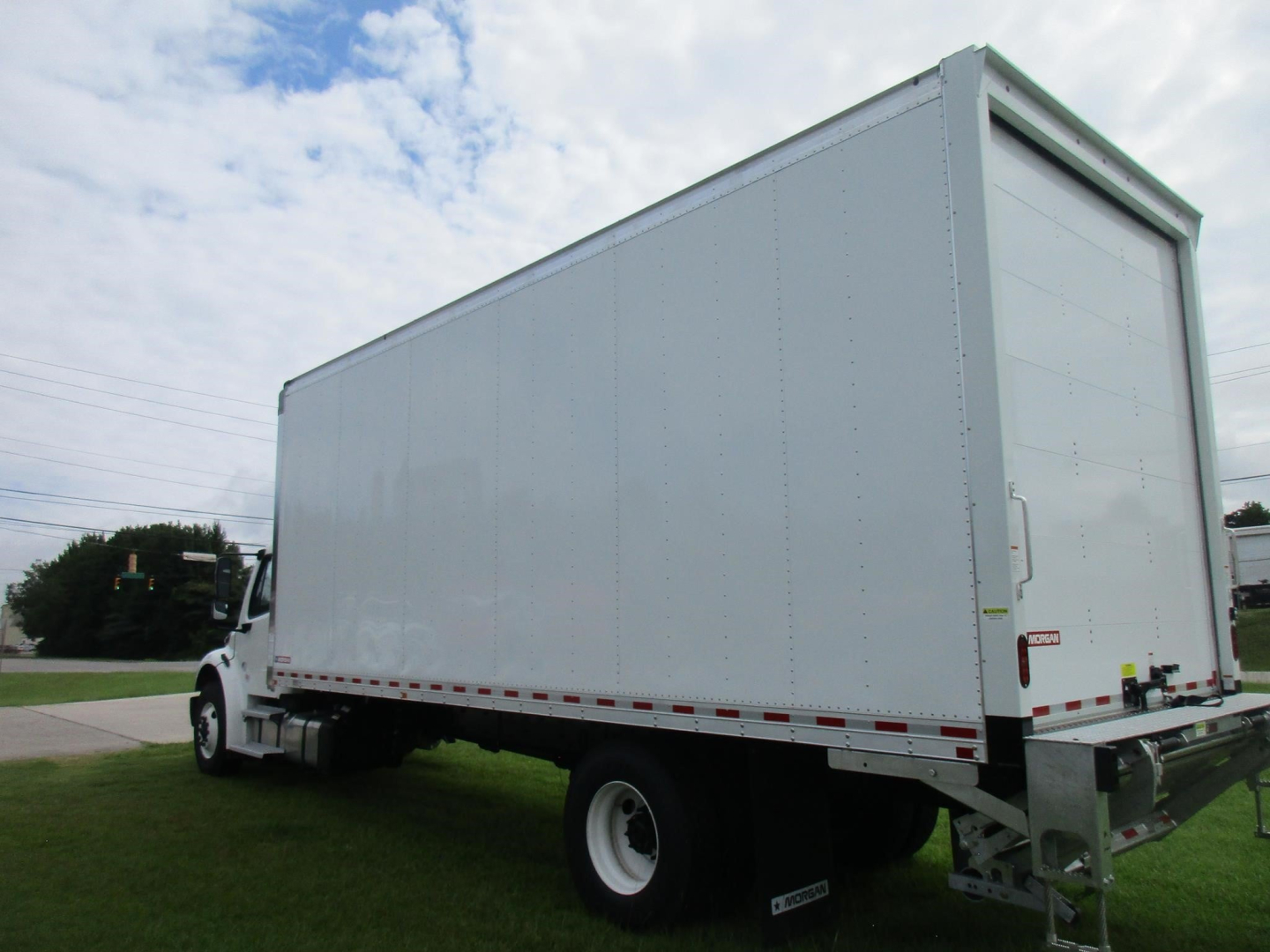 Freightliner M2 106 box truck side/rear view with tall cargo box, white exterior, chassis cab, ladder frame, and rear bumper
