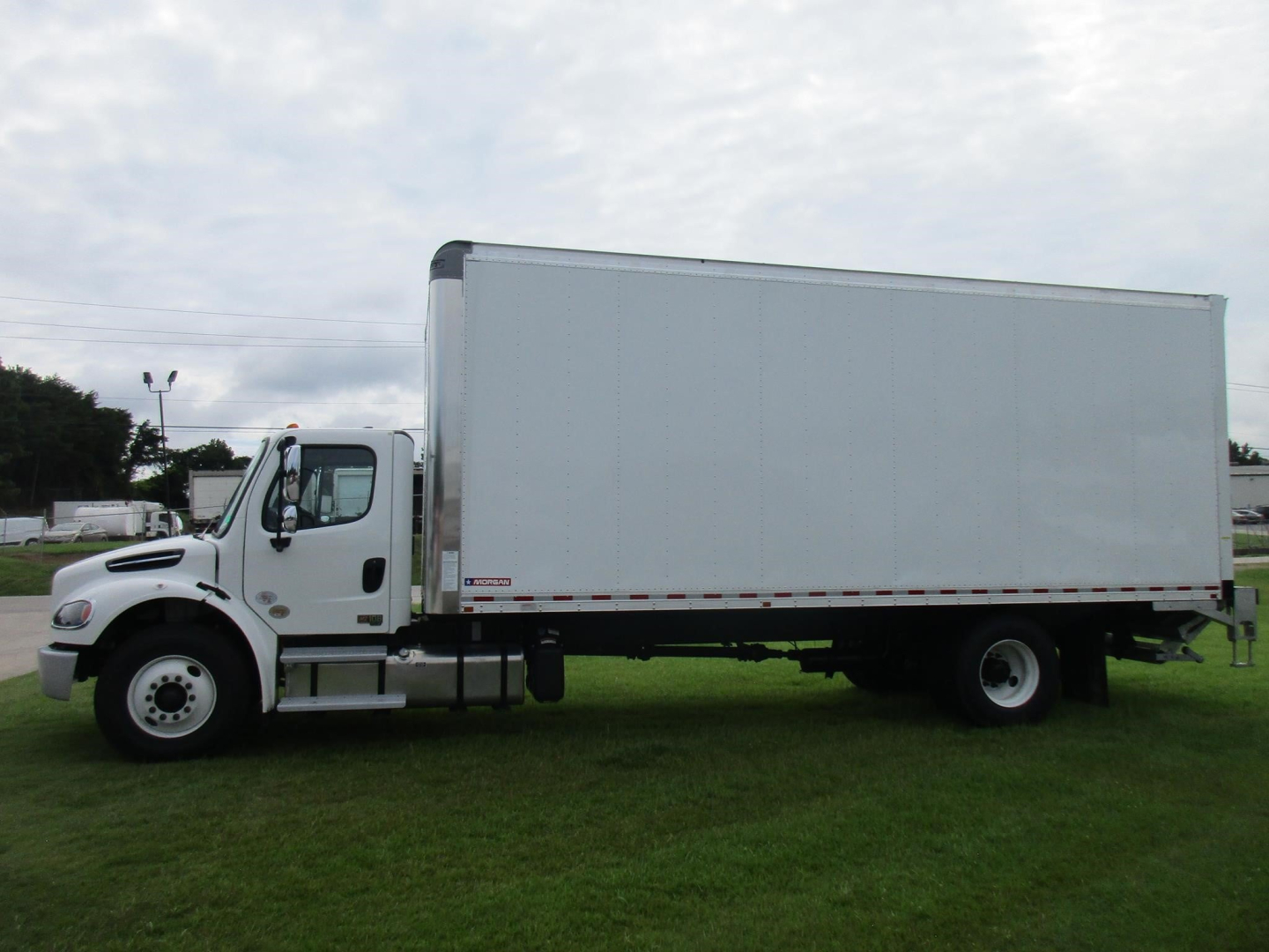 Box truck side view showing Freightliner M2 106 with white cab and large rectangular cargo box.