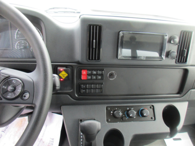 Dashboard of a Freightliner M2 106 showing steering wheel, digital display, control panel, climate controls, and cup holder area.