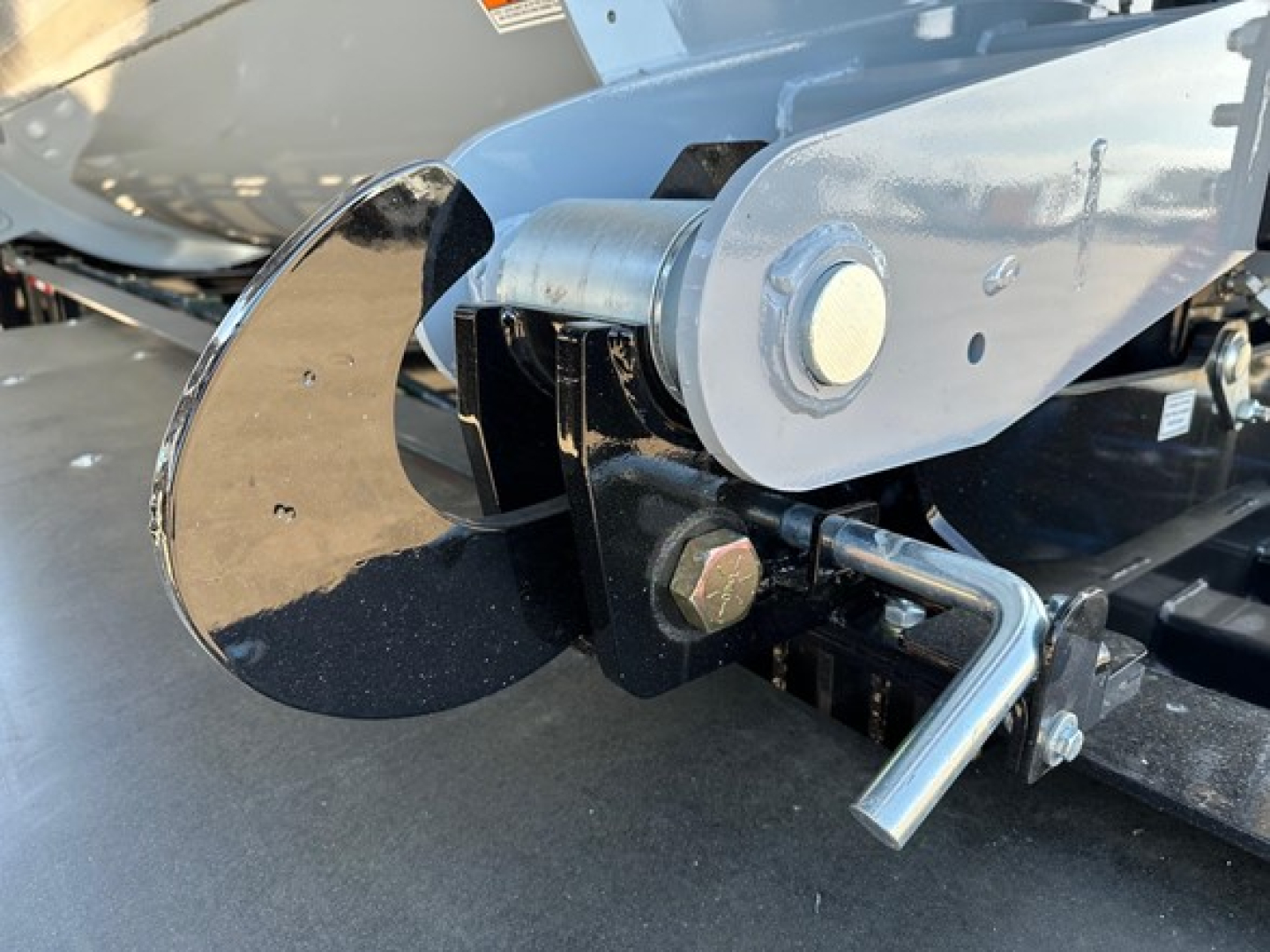 Jet air ride side dump trailer hitch mechanism with blue frame and bolt, showing a curved black blade and a locking pin.