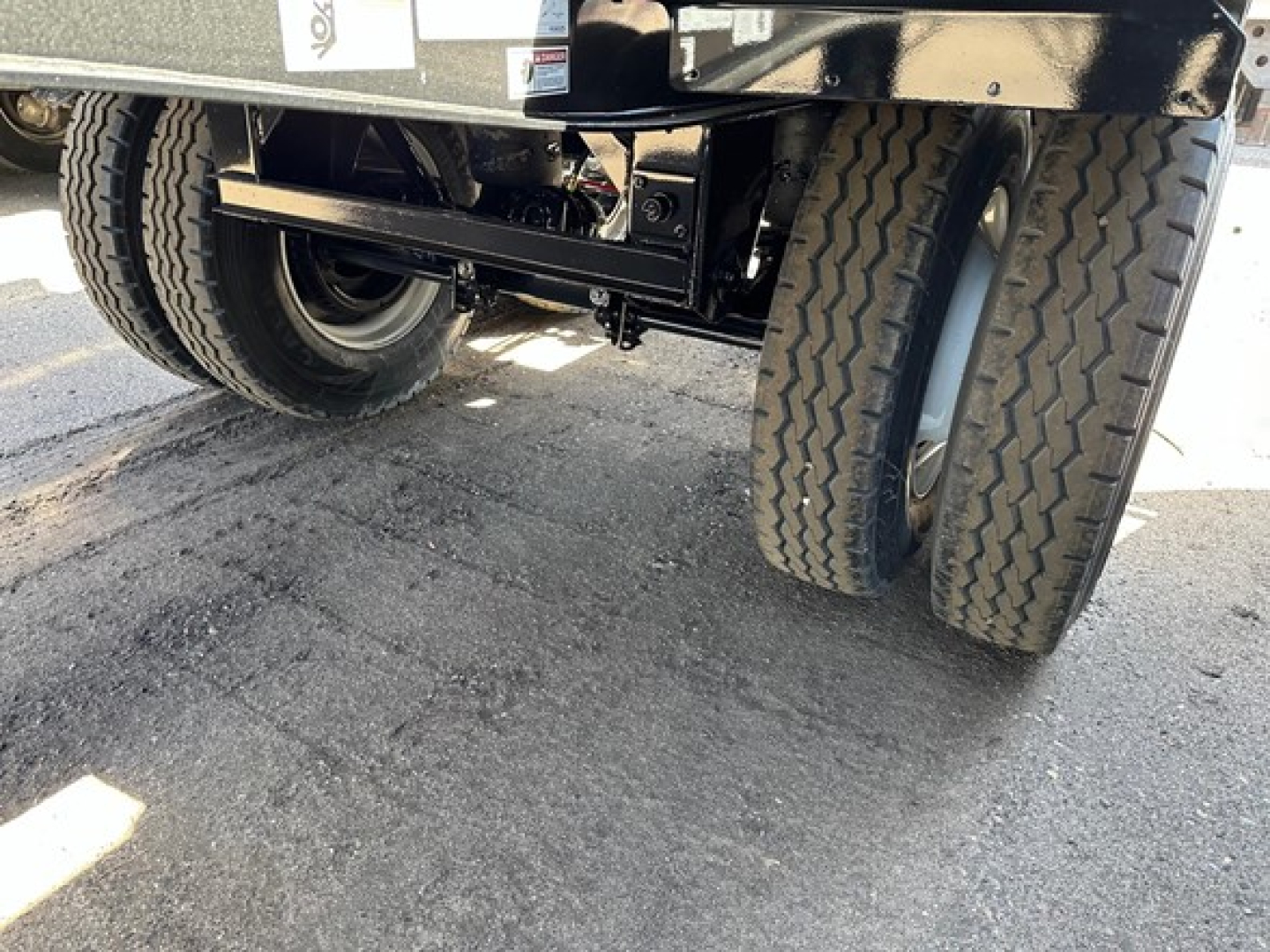 Dual rear axles of a new Jet Air Ride Side Dump trailer showing heavy-duty suspension and tires, undercarriage components visible.