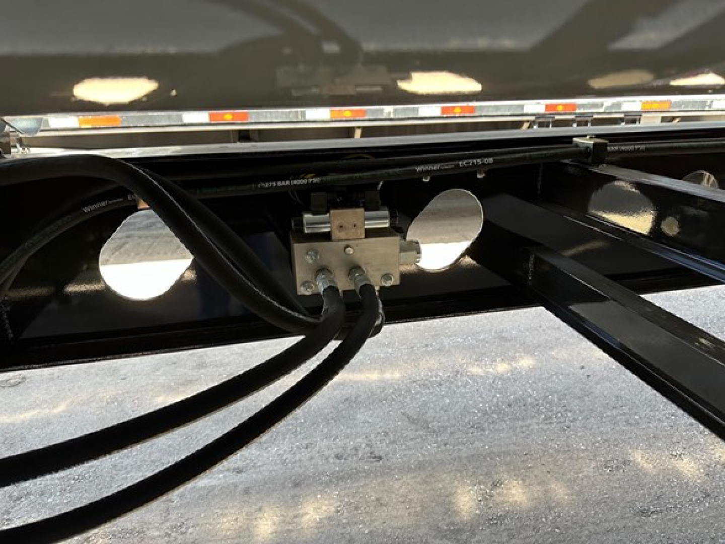 Trailer undercarriage showing hydraulic lines and mounting bracket for Jet Air Ride side dump trailer.