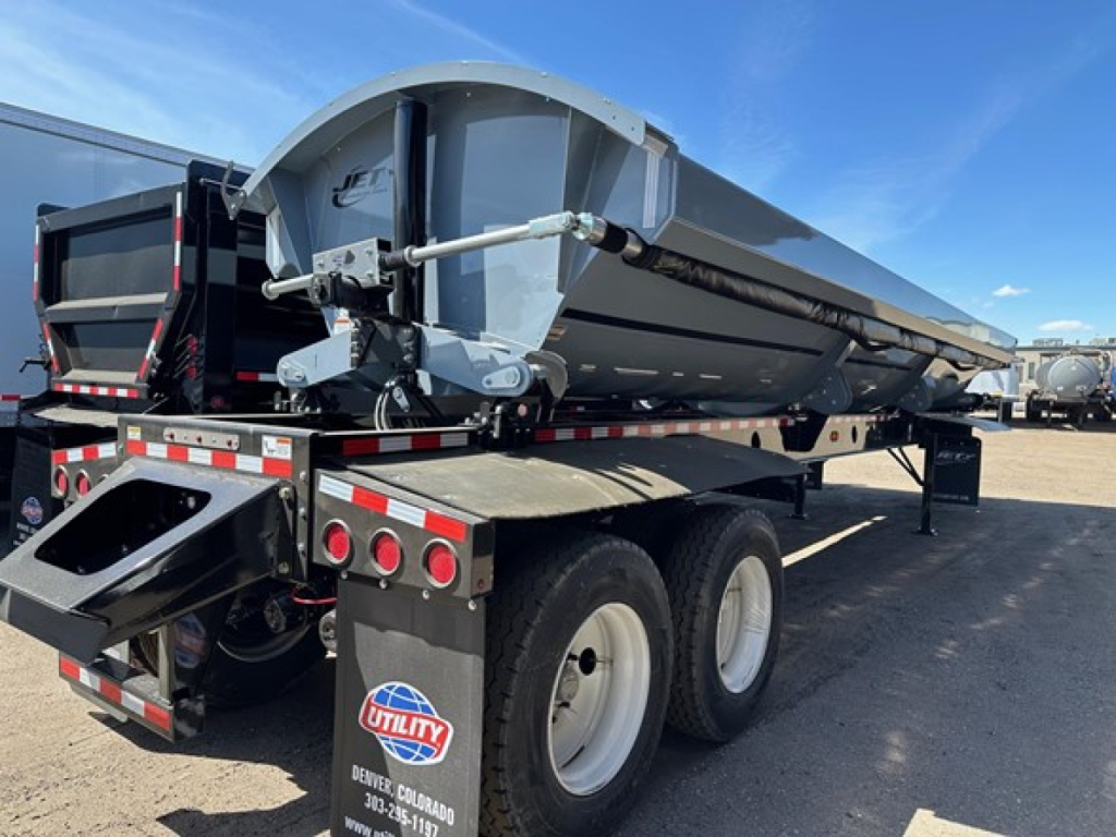 Dump trailer with Jet Air Ride side dump system. Visible are rear lights, dual rear axles, wheels, and a hydraulic lift assembly. Sticker reads ‘UTILITY’ with a Denver, Colorado tag.