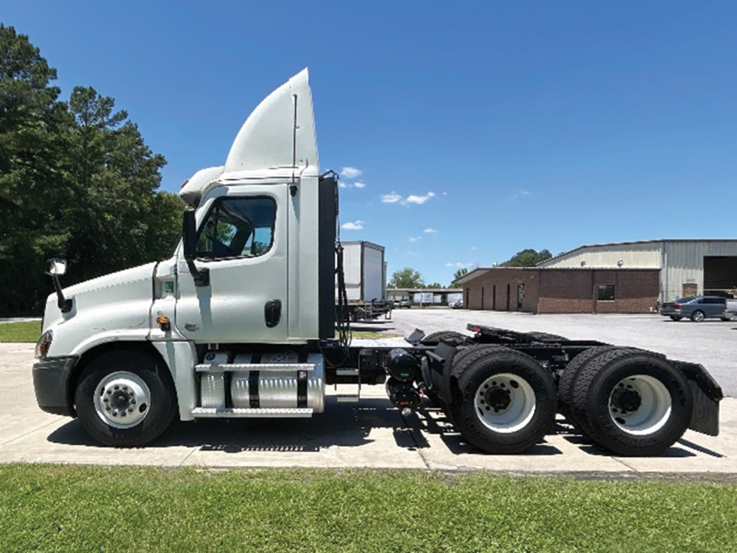 Truck side view of a 2020 Freightliner Cascadia125 daycab showing cab, fuel tanks, and rear dual-axle configuration.
