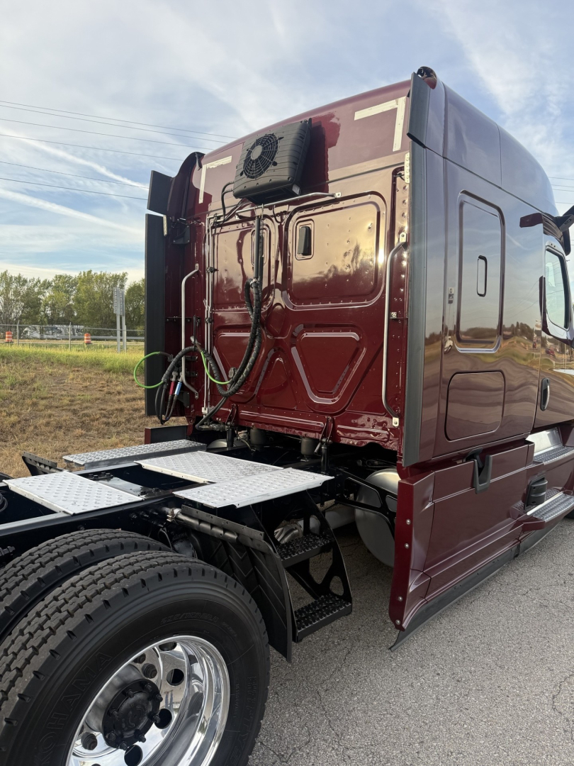 Rear view of a maroon 2021 Freightliner Cascadia 126 tractor cab with sleeper, showing back panel and air lines connected to fifth wheel area.