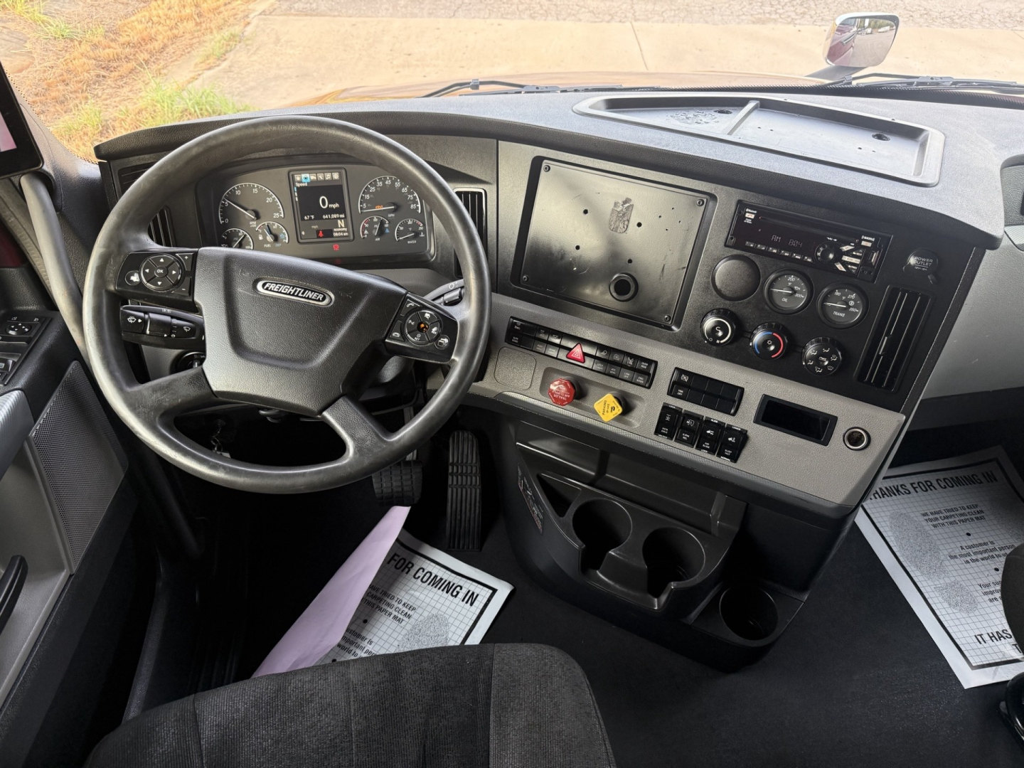Cab interior of a 2021 Freightliner Cascadia 126 showing steering wheel, dashboard, and center console with gauges and controls.