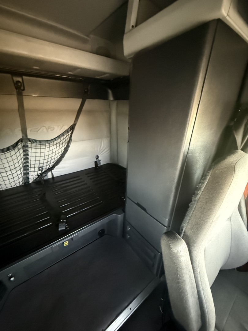 Freightliner Cascadia126 sleeper cab interior showing cargo area with netting and vertical partition.