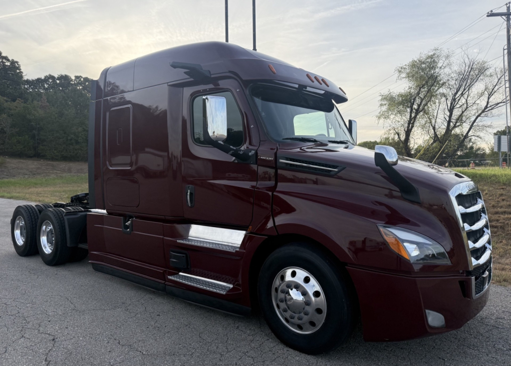 Freightliner Cascadia126 tractor in maroon showing side cab, front grille, chrome mirrors, dual rear axles, and tanker windows.