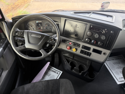 Dashboard and steering wheel of a Freightliner Cascadia truck cab, cab controls and digital display visible.