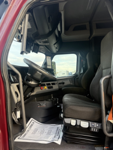 Freightliner Cascadia126 truck interior cab shot showing driver's seat, steering wheel, dashboard gauges, and window view.