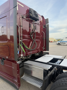 Rear view of a Freightliner Cascadia126 cab with exposed hoses and connectors on the back panel, metal step, and dual rear tires.