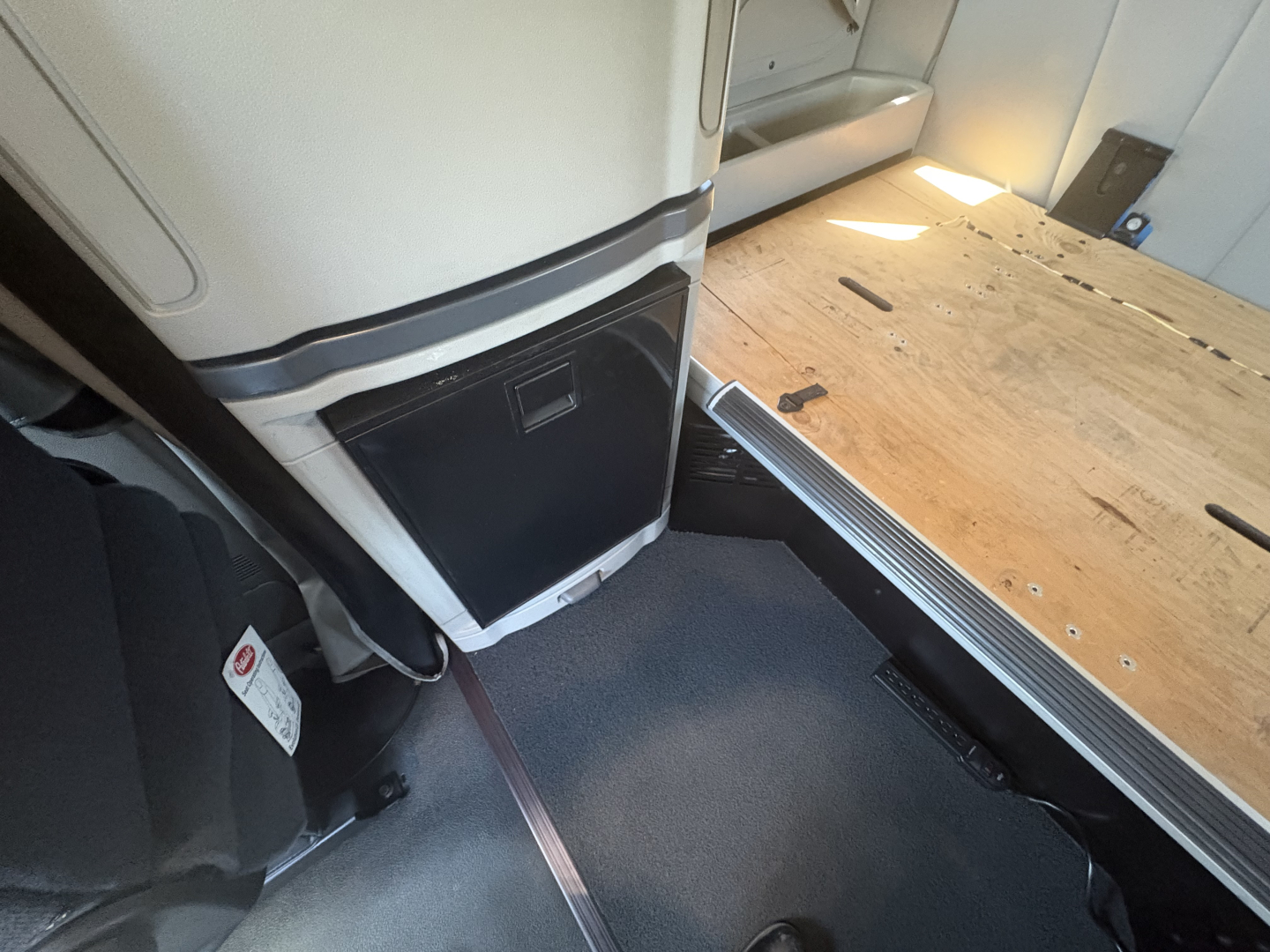 Peterbilt 579 interior view of cab area showing entry step and part of sleeper with wooden bed platform and gray flooring.