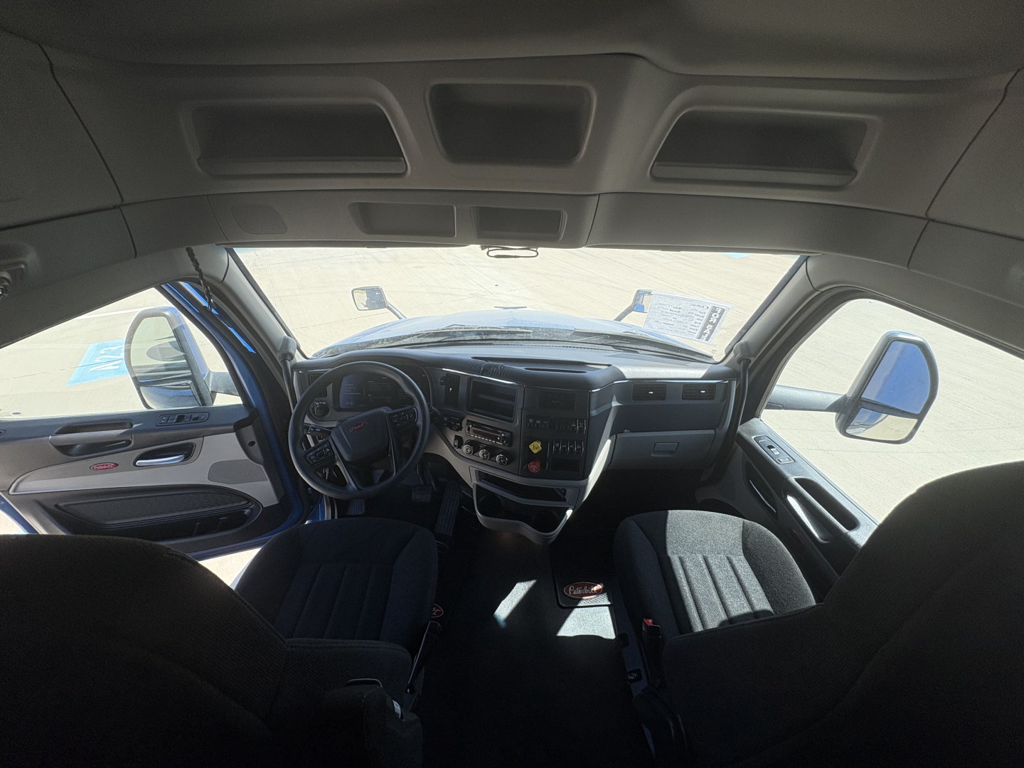 Peterbilt 579 cab interior dashboard view with steering wheel, instrument cluster, and driver/passenger seats.