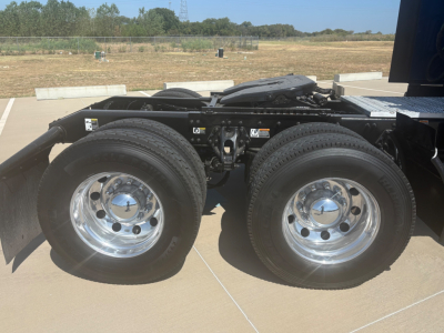 Twin rear axles with chrome wheels and dual tires on a Peterbilt truck chassis, flatbed area visible, no license plate.